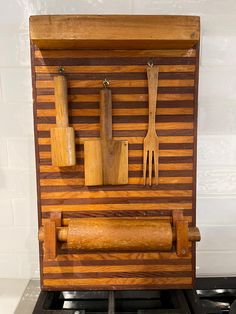 a wooden stove top with utensils and knives mounted on the back of it