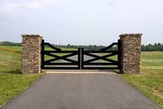 a gated entrance to a grassy field with trees in the background and grass on either side