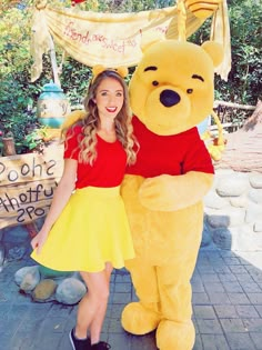 a woman standing next to a large winnie the pooh mascot