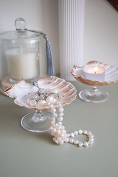 two seashells and a candle are sitting on the table next to each other