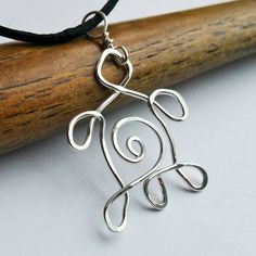 a silver wire pendant sitting on top of a wooden stick