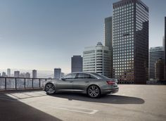 a silver car is parked in front of some tall buildings and the sun shines on it