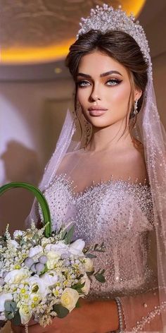 a woman in a wedding dress holding a bouquet and wearing a tiara with pearls on it