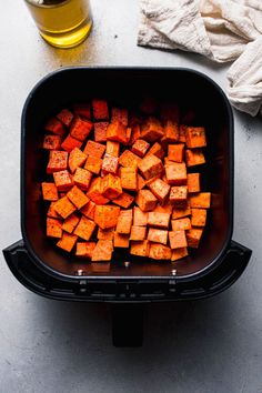 cubed sweet potatoes in a black container next to a glass of beer