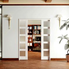 an open door leading to a living room with bookshelves and a potted plant