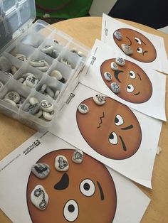 several buttons with faces on them sitting on top of a table next to an open plastic container