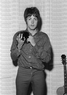 black and white photograph of a man holding a cell phone in front of a guitar