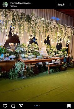 a table topped with lots of white flowers next to a wall covered in greenery