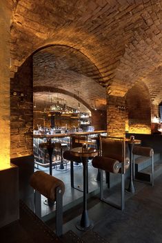 the interior of a restaurant with brick walls and stone floors, along with bar stools