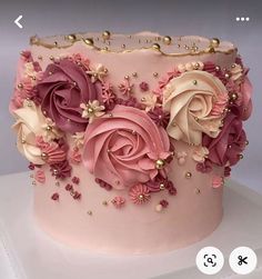 there is a pink cake with flowers on the top and gold beads around the edges