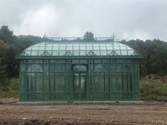 a large green building sitting on top of a dirt field