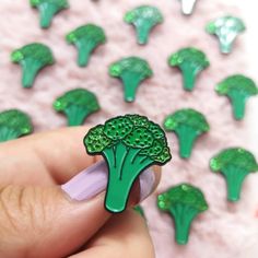 a person is holding a broccoli pin in front of some other broccoli florets