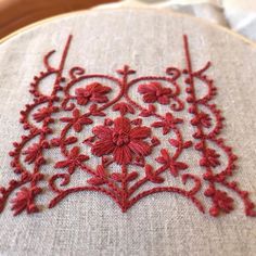 a close up of a embroidery on a piece of cloth with red thread and flowers