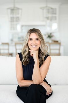 a woman sitting on top of a couch with her chin resting on her hand and looking at the camera