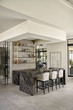 an elegant kitchen with marble counter tops and bar stools in the middle of the room