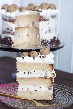 a slice of cake with white frosting and chocolate chip cookies on top is sitting on a glass plate