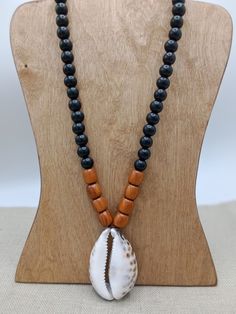 The necklace is 26 inches long and closes with a clasp. The cowrie shell is approximately 2.10 inches wide and 3 inches long. The beads are wood on a leather cord. If you have any questions please feel free to contact us at anytime. Black Artisan Necklaces For Beach, Black Artisan Necklace For Beach, Artisan Black Necklace For Beach, Brown Necklaces With Black Beads For Beach, Artisan Black Jewelry For The Beach, Black Necklaces With Large Beads For Beach, Black Wooden Beads Necklace For Beach, Spiritual Black Beads Jewelry For Beach, Spiritual Black Beaded Jewelry For Beach