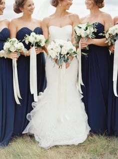 the bride and her bridesmaids are all dressed in navy blue dresses with white bouquets