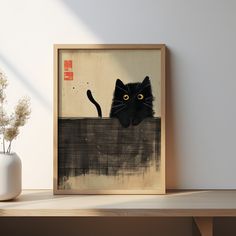 a black cat with yellow eyes peeking out from behind a piece of artwork on a shelf