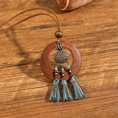 a wooden necklace with tassels hanging from it's side on a table