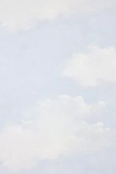 an image of two sheep grazing in the grass by some trees and clouds on a sunny day