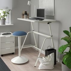 a white desk with a laptop on it next to a potted plant and other items