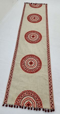 a white table runner with red circles and tassels on the top, along with pom - poms