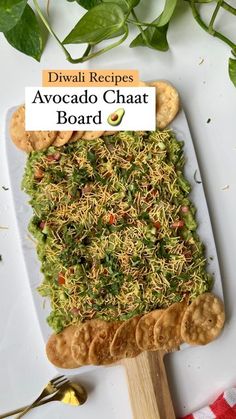 a white plate topped with an avocado cheese board and crackers next to green leaves