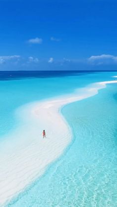 people are walking on the beach in clear blue water