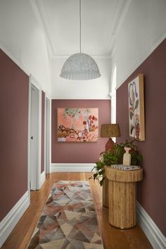 a long hallway with red walls and wooden flooring on both sides is decorated with an area rug