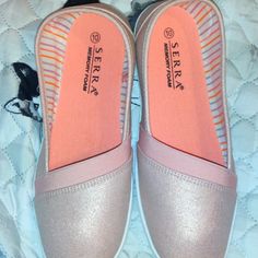 two pairs of pink and silver slippers on a bed