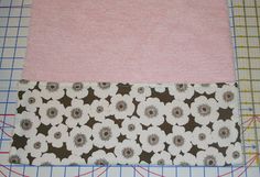 a piece of fabric with flowers on it next to a ruler and cutting mat that is being cut