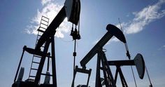 the silhouette of oil pumps against a blue sky