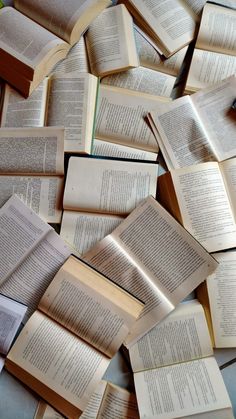 many open books laying on top of each other in the middle of a pile,