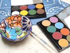 a bowl with some paint on it next to other paints and brushes in front of them