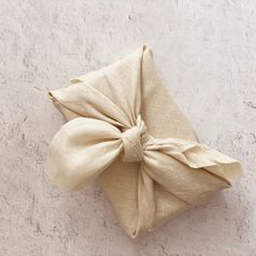 a white pillow with a bow on it sitting on a floor next to a wall