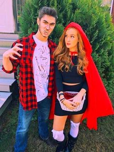 a man standing next to a woman wearing a red hoodie and black dress in front of a house