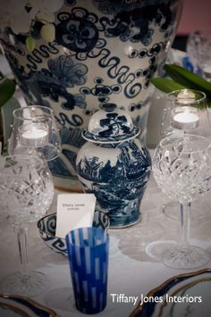 blue and white vases are on the table with other glassware in front of them