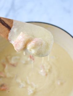 a wooden spoon with some food in it on top of a pan filled with soup