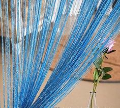 a vase filled with blue string next to a pink flower on top of a table