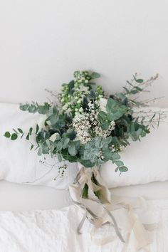 a bouquet of greenery on a white bed