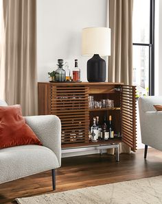 a living room with two couches and a cabinet in the corner that has liquor bottles on it