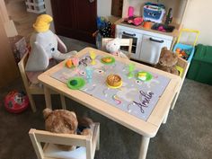 two teddy bears sitting at a table in a play room