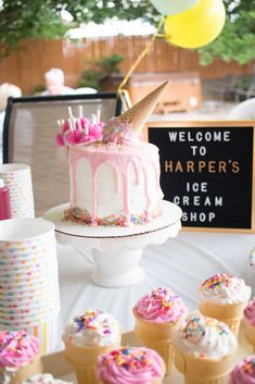 a table topped with lots of cupcakes covered in frosting and sprinkles