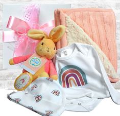 a baby gift basket with a stuffed rabbit, blanket, booties and other items