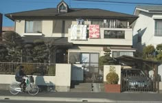 a person riding a bike in front of a house with laundry hanging from the roof