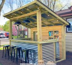 an outdoor bar with several stools and lights on it's roof, in front of a house