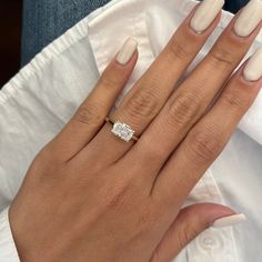 a woman's hand with white manicured nails and an engagement ring