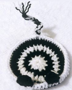 a black and white crocheted ornament hanging from a string on a white surface