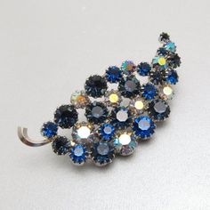 Vintage blue rhinestone leaf has varying colors of blue stones in all prong settings and set in silver tone metal.  Nice sparkle from some ab coated stones.  Measures about 2 1/2 inches X 1 1/4 inch. Unsigned, excellent vintage condition.  (Matching earrings listed separately)Find lots more vintage jewelry at Purple Daisy Jewelry!http://www.etsy.com/shop/purpledaisyjewelryThanks a bunch for shopping for vintage jewelry at Purple Daisy Jewelry on Etsy! Flower Costume, Daisy Jewelry, Vintage Rhinestone Brooch, Purple Daisy, Leaf Brooch, Blue Stones, Bird Jewelry, Brooch Jewelry, Old Jewelry